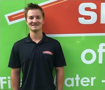 Young man standing in front of the SERVPRO of St. Cloud trailer. 