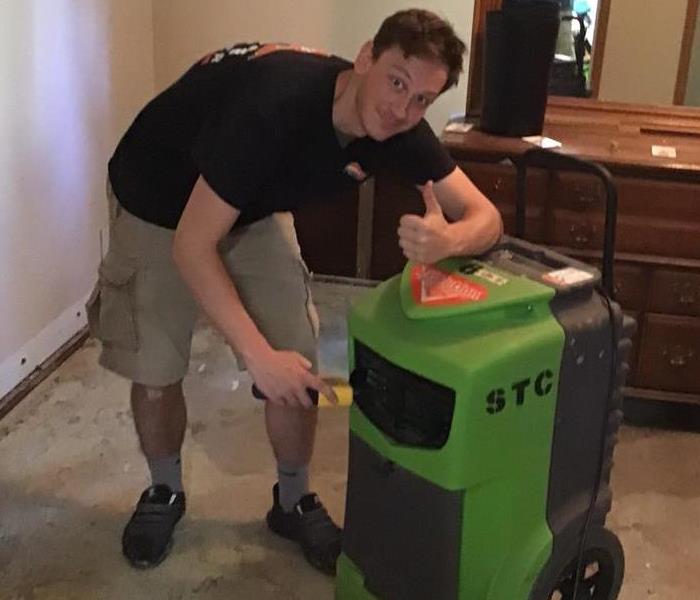 SERVPRO crew member standing next to a green machine used to take moisture out of the air.