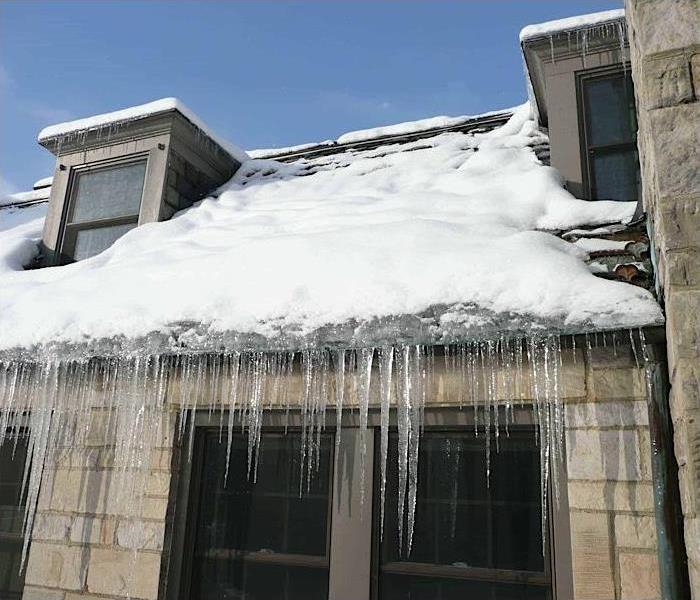 House with snow and ice hanging from the roof.