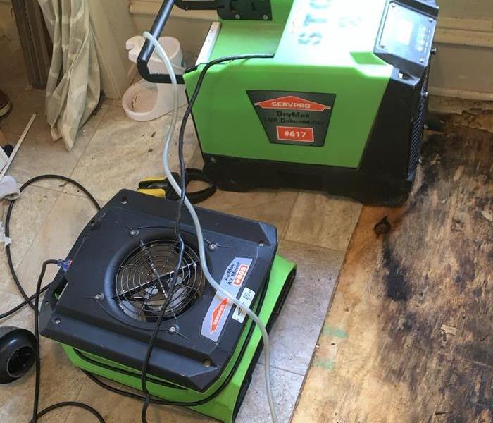 Green SERVPRO drying equipment on the ground of a basement. 